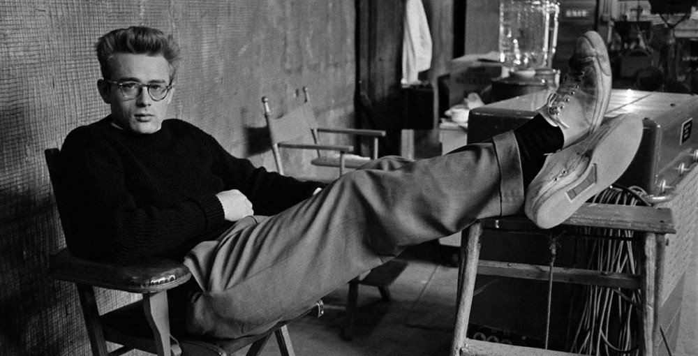 Man in black shirt lying on a chair with his legs on another chair.