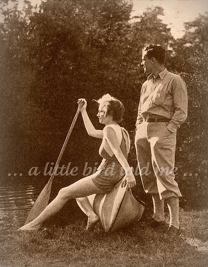 A man and woman standing next to a canoe, holding a canoe paddle.