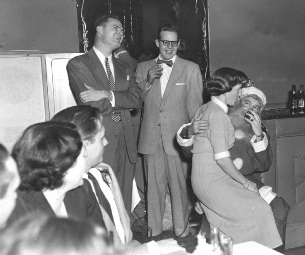Vintage woman sitting on santa lap in holiday party.