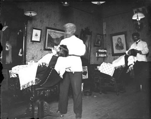 A man is getting a Straight Razor Shave in a barber shop.
