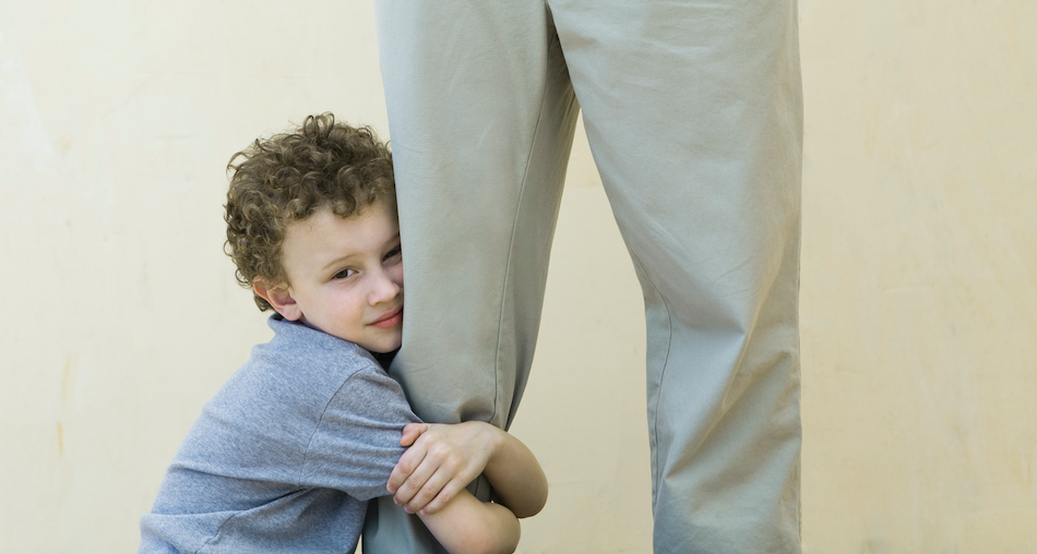 A young boy hugs his father's leg, offering comfort and security in moments of childhood anxiety.